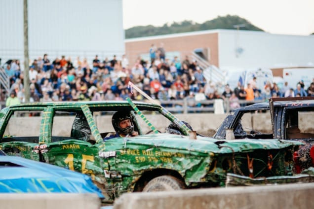 Demolition derby in front of a cheering crowd.