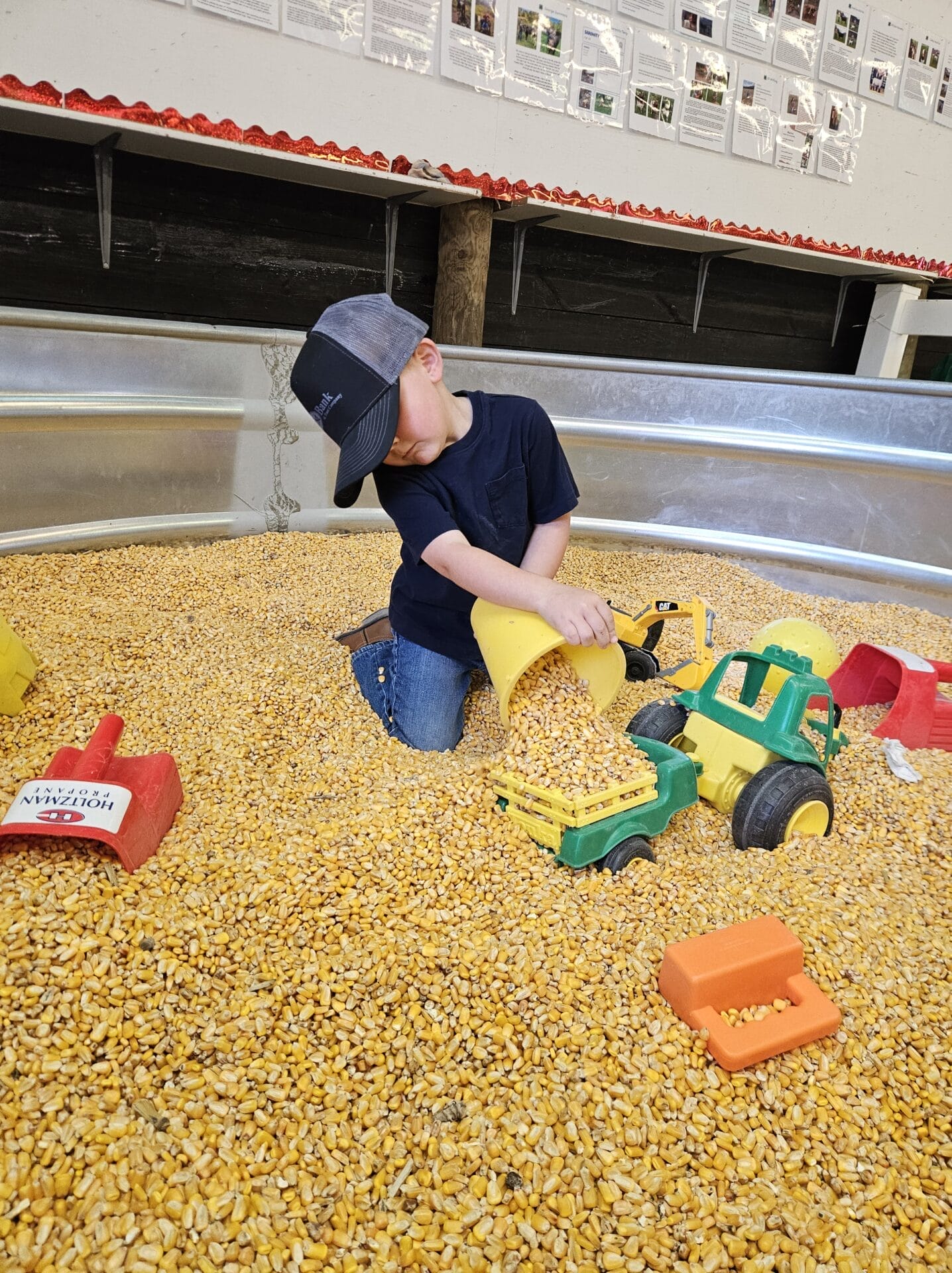 Child playing with toy trucks in corn kernels